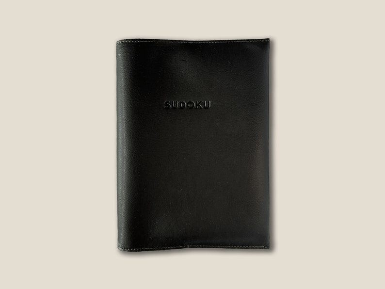 May include: Black leather notebook with the word "SUDOKU" embossed on the front cover.