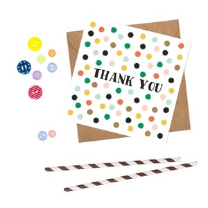 Puede incluir: Una tarjeta blanca con un patr&oacute;n de lunares de colores y el texto "THANK YOU" en negro. La tarjeta est&aacute; sobre un sobre marr&oacute;n.