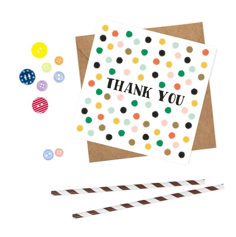Puede incluir: Una tarjeta blanca con un patr&oacute;n de lunares de colores y el texto "THANK YOU" en negro. La tarjeta est&aacute; sobre un sobre marr&oacute;n.