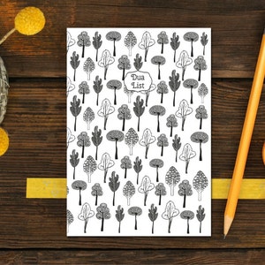 May include: A white notebook with a black and white pattern of trees. The notebook has the words "Dua List" written on the front.