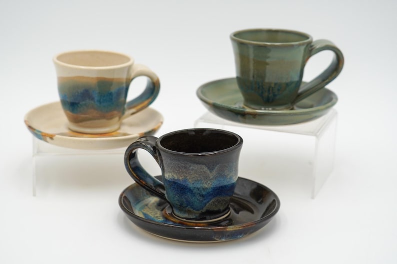May include: Three ceramic teacups and saucers with blue and brown glaze. The cups are all different colors and have a unique glaze pattern.