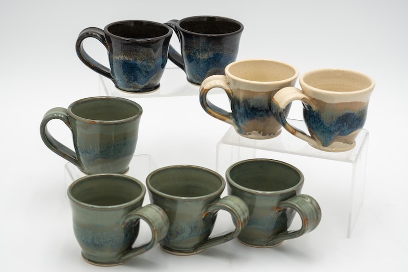 May include: Set of eight ceramic mugs with blue, green, and brown glaze. The mugs have a variety of shapes and sizes.