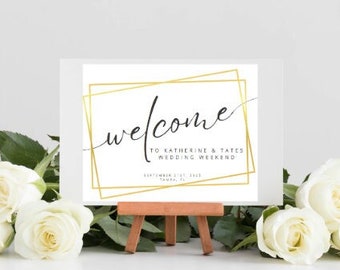 May include: Editable wedding welcome sign with a gold frame and the text "Welcome to Katherine & Tates Wedding Weekend". The sign is on a small wooden easel.