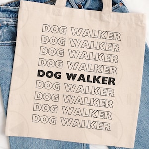 May include: A beige canvas tote bag with the words "DOG WALKER" printed in black. The text is repeated multiple times. The bag is placed on top of a pair of blue jeans.