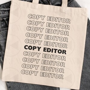 May include: A beige canvas tote bag featuring the text COPY EDITOR repeated ten times in a vertical column. The text is printed in a black outline font, except for the seventh line which is in solid black. The bag has two matching fabric handles.