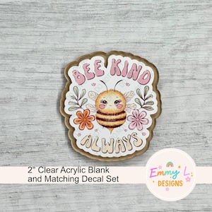 May include: A 2 inch clear acrylic blank with a matching decal featuring a cartoon bee with flowers and the text "Bee Kind Always".