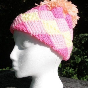 May include: A pink and yellow crocheted hat with a pink pom-pom on top.