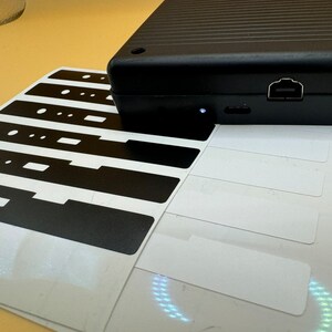 May include: A set of black and white stickers with a black rectangular shape and a white border. The stickers are arranged in a row on a white surface.