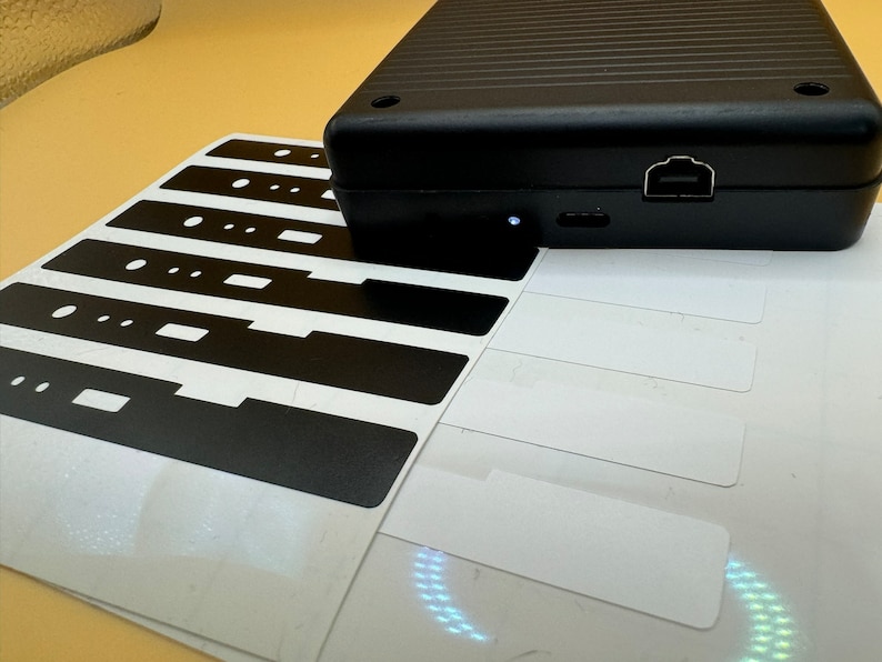 May include: A set of black and white stickers with a black rectangular shape and a white border. The stickers are arranged in a row on a white surface.
