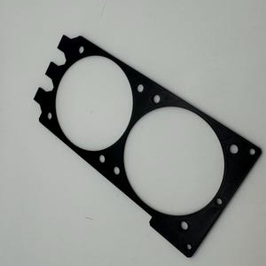 Peut inclure: Mod&egrave;le en plastique noir avec deux d&eacute;coupes circulaires. Le mod&egrave;le a un bord dentel&eacute; en haut et un bord lisse en bas.