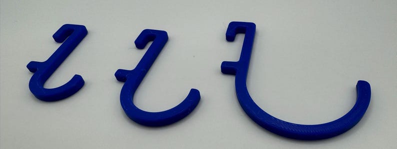 Puede incluir: Tres ganchos de pl&aacute;stico azul de diferentes tama&ntilde;os. Los ganchos tienen forma de 'J' y est&aacute;n dise&ntilde;ados para colgar objetos.