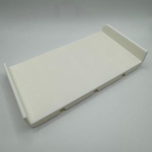 May include: A white plastic tray with three small holes on the bottom. The tray has rounded edges and a smooth surface.