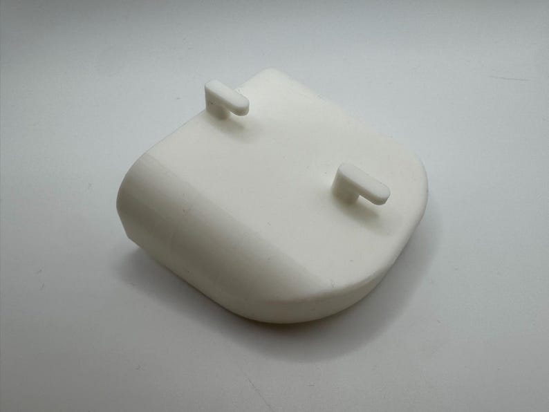 K&ouml;nnte beinhalten: Ein wei&szlig;es Kunststoffbauteil mit abgerundeter Form und zwei kleinen, rechteckigen Vorspr&uuml;ngen. Das Objekt hat eine glatte, matte Oberfl&auml;che und ist wahrscheinlich Teil einer gr&ouml;&szlig;eren Baugruppe. Das Design ist einfach und funktional.