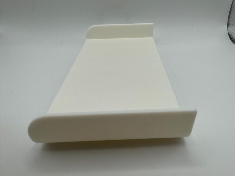 May include: A white plastic tray with rounded edges. The tray is designed to be used as a laptop stand.