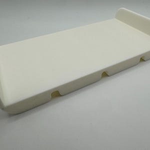 May include: White plastic tray with three indented sections. The tray is rectangular and has rounded edges.