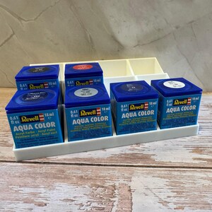 Peut inclure: Ensemble de peintures acryliques Revell Aqua Color en pots bleus carr&eacute;s, chacun contenant 18 ml. Les pots sont dispos&eacute;s dans un organisateur en plastique blanc. Id&eacute;al pour la peinture de maquettes.
