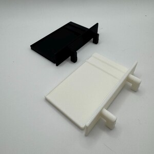 May include: Two plastic shelf brackets, one black and one white. The brackets are rectangular in shape with two small tabs on the side.