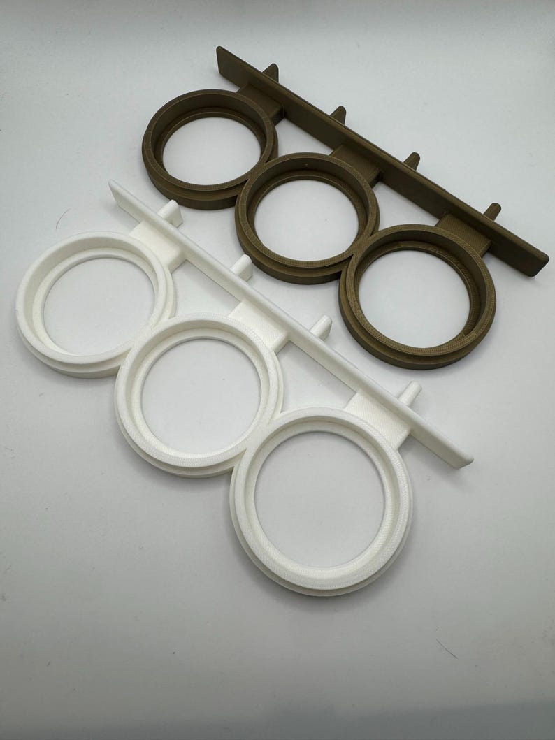 May include: Two sets of three round, white and brown plastic holders for displaying items like candles or small plants. The holders are attached to a rectangular base.