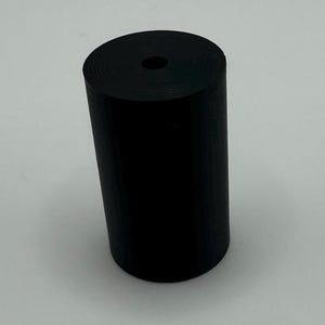 May include: A black rubber cylinder with a hole in the center.