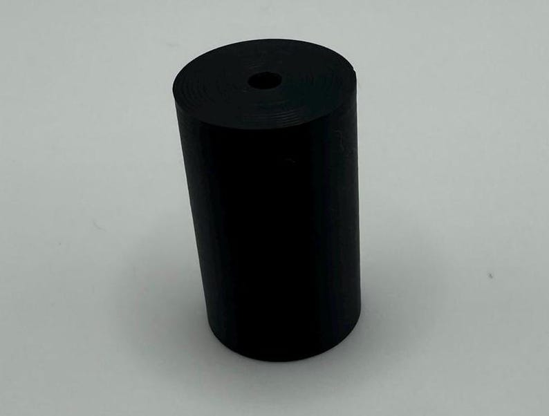 May include: A black rubber cylinder with a hole in the center.