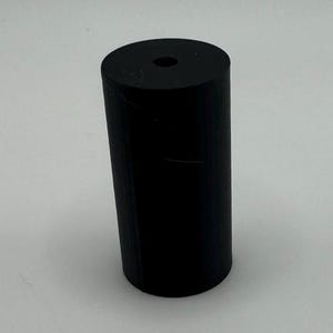 May include: A black rubber cylinder with a hole in the top.