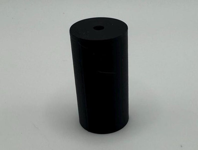 May include: A black rubber cylinder with a hole in the top.