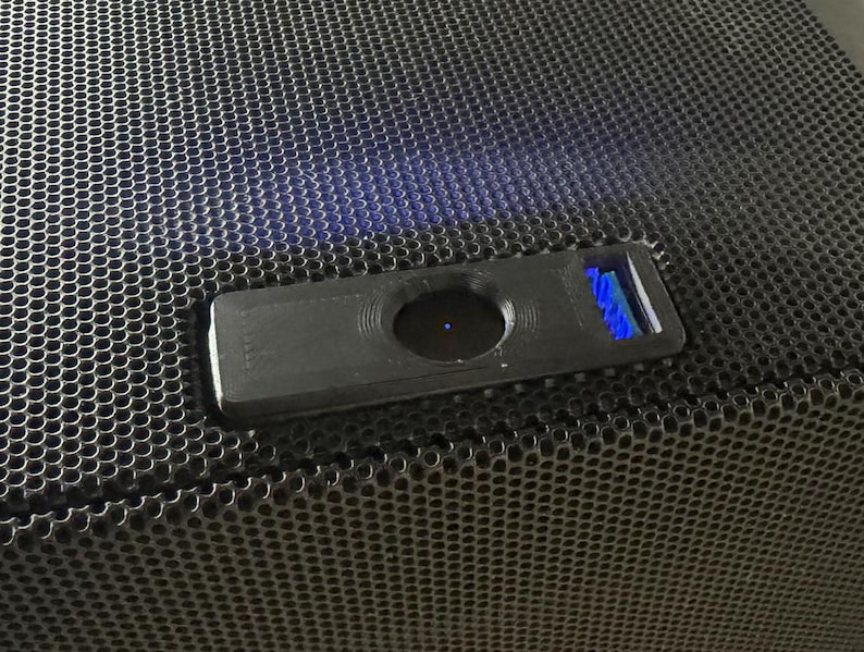 Pu&ograve; includere: Un altoparlante nero con una griglia in metallo nero e un piccolo pulsante rettangolare nero con una luce blu.