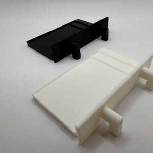 May include: Two plastic shelf brackets, one black and one white. The brackets are rectangular in shape with two small tabs on the side.