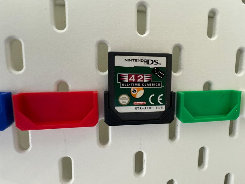 May include: A black Nintendo DS game cartridge with a white label. The label features the text "42 All-Time Classics" and a picture of a billiard ball. The cartridge is in a clear plastic case with a green and red plastic holder.
