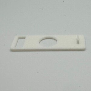 Pu&ograve; includere: Pezzo di plastica bianco con un foro rotondo e una piccola apertura rettangolare.