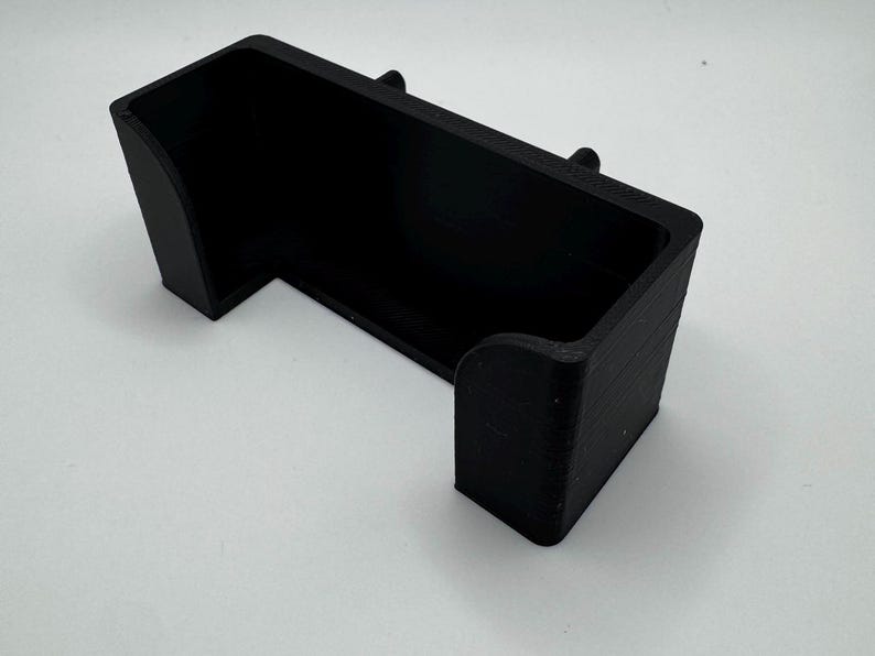 Pu&ograve; includere: Un supporto per telefono in plastica nera con un design curvo. Il supporto &egrave; progettato per tenere un telefono in posizione verticale.