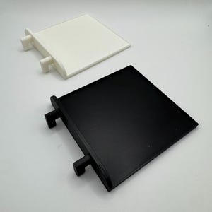 Pode incluir: Dois suportes de prateleira de pl&aacute;stico quadrados, um branco e um preto, com duas abas de cada lado para montagem.