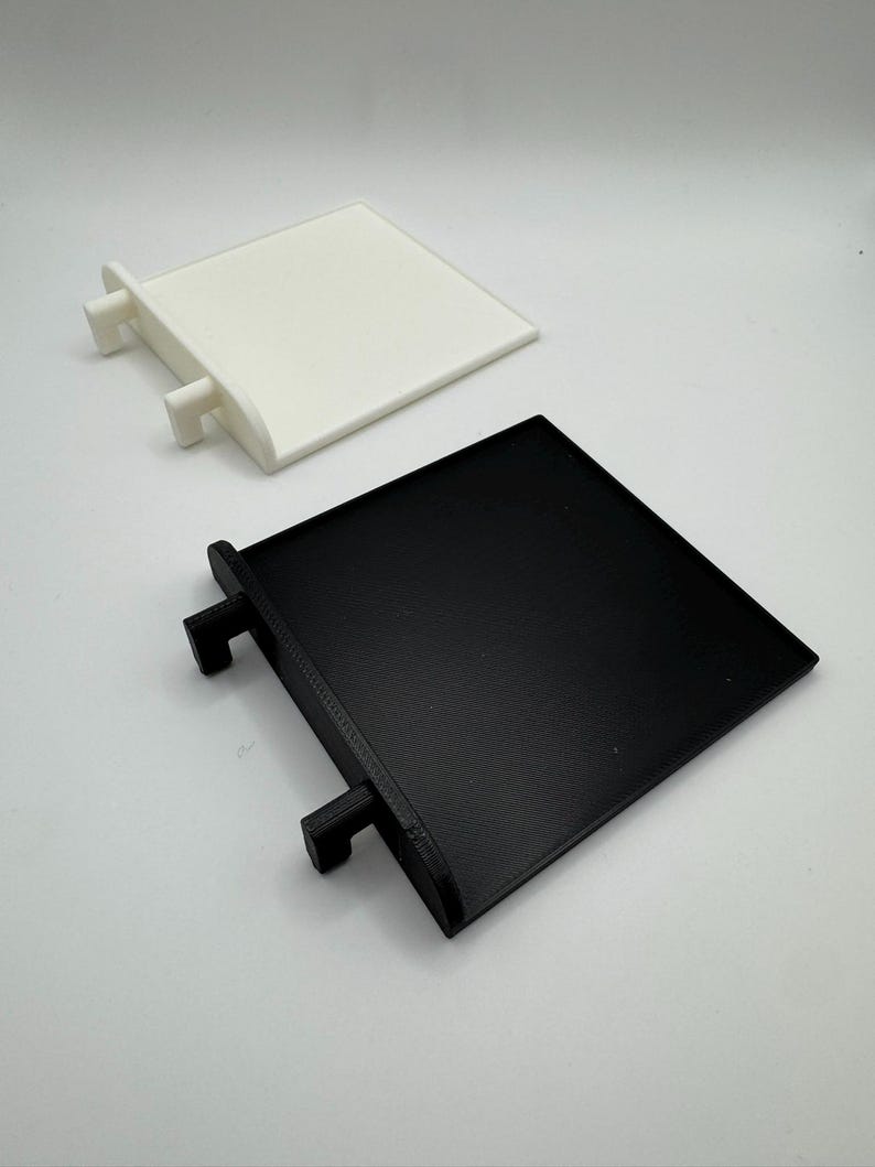 Pode incluir: Dois suportes de prateleira de pl&aacute;stico quadrados, um branco e um preto, com duas abas de cada lado para montagem.