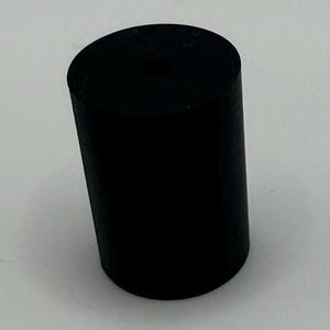 May include: A black rubber cylinder with a hole in the center. The cylinder is about 2 inches in diameter and 3 inches tall.