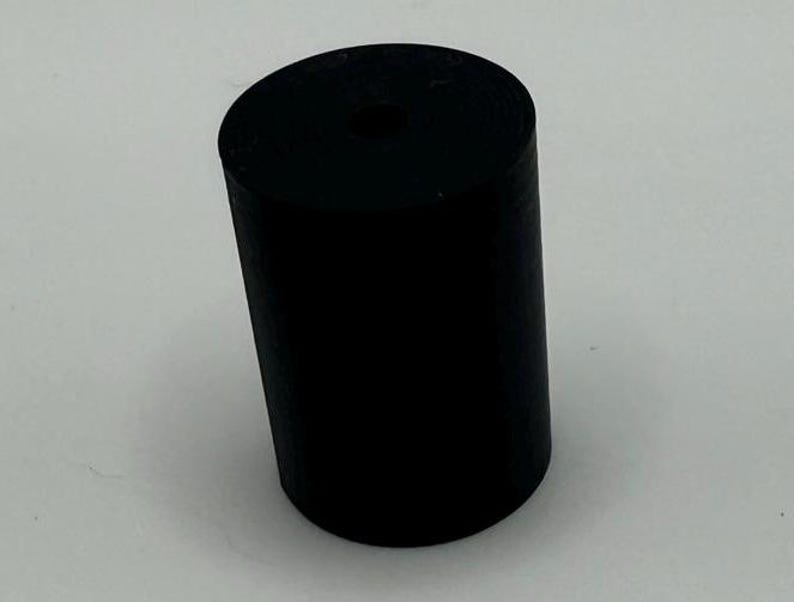 May include: A black rubber cylinder with a hole in the center. The cylinder is about 2 inches in diameter and 3 inches tall.