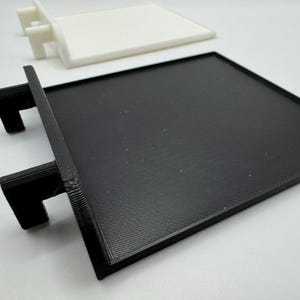 Pode incluir: Dois suportes de prateleira de pl&aacute;stico preto com uma superf&iacute;cie texturizada. Os suportes s&atilde;o projetados para serem montados em uma parede ou outra superf&iacute;cie.