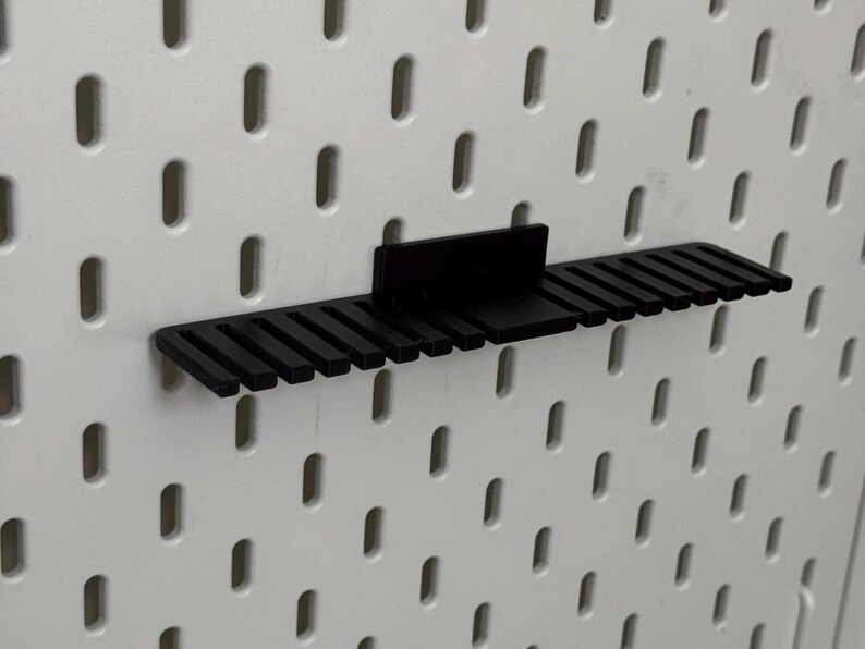 K&ouml;nnte beinhalten: Schwarzer Kunststoff-Pegboard-Organizer mit 16 Steckpl&auml;tzen zum Aufbewahren von Werkzeugen oder anderen kleinen Gegenst&auml;nden.