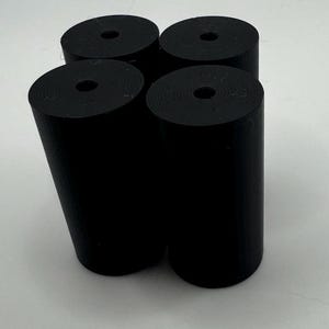 May include: Four black cylindrical objects with a hole in the center. The objects are arranged in a square shape.
