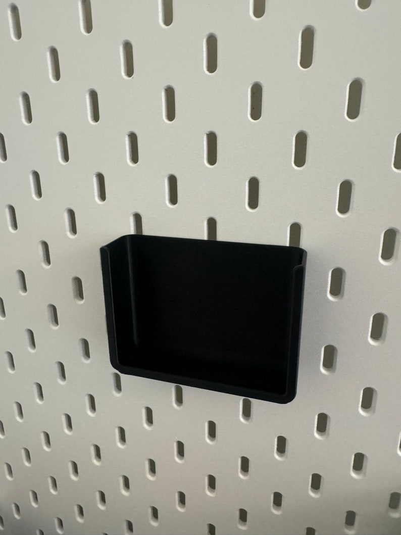 Op de afbeelding: Een zwart plastic pegboard-plank met een witte achtergrond.
