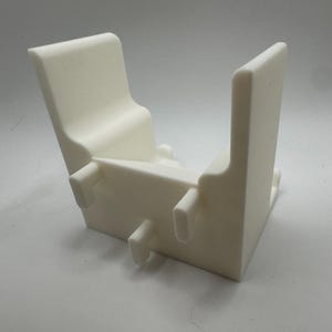 K&ouml;nnte beinhalten: Ein wei&szlig;es, eckiges, 3D-gedrucktes Objekt mit U-f&ouml;rmigem Design. Es hat zwei aufrechte, rechteckige Seiten, die durch eine Basis mit drei kleinen, zylindrischen Vorspr&uuml;ngen verbunden sind. Das Objekt hat eine glatte, matte Oberfl&auml;che und scheint aus Kunststoff zu sein.