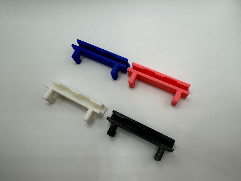 Pode incluir: Quatro clipes de cabo de pl&aacute;stico em diferentes cores: azul, rosa, branco e preto. Os clipes s&atilde;o projetados para segurar os cabos no lugar.