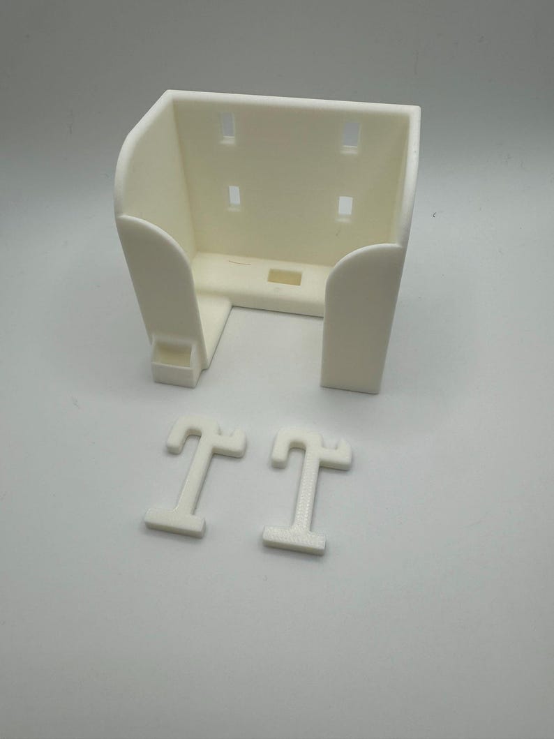 May include: A cream-colored, 3D-printed wall-mounted holder with a rectangular shape and rounded edges. The holder has four rectangular slots and two T-shaped mounting pieces. The design is simple and functional, suitable for various organizational purposes.