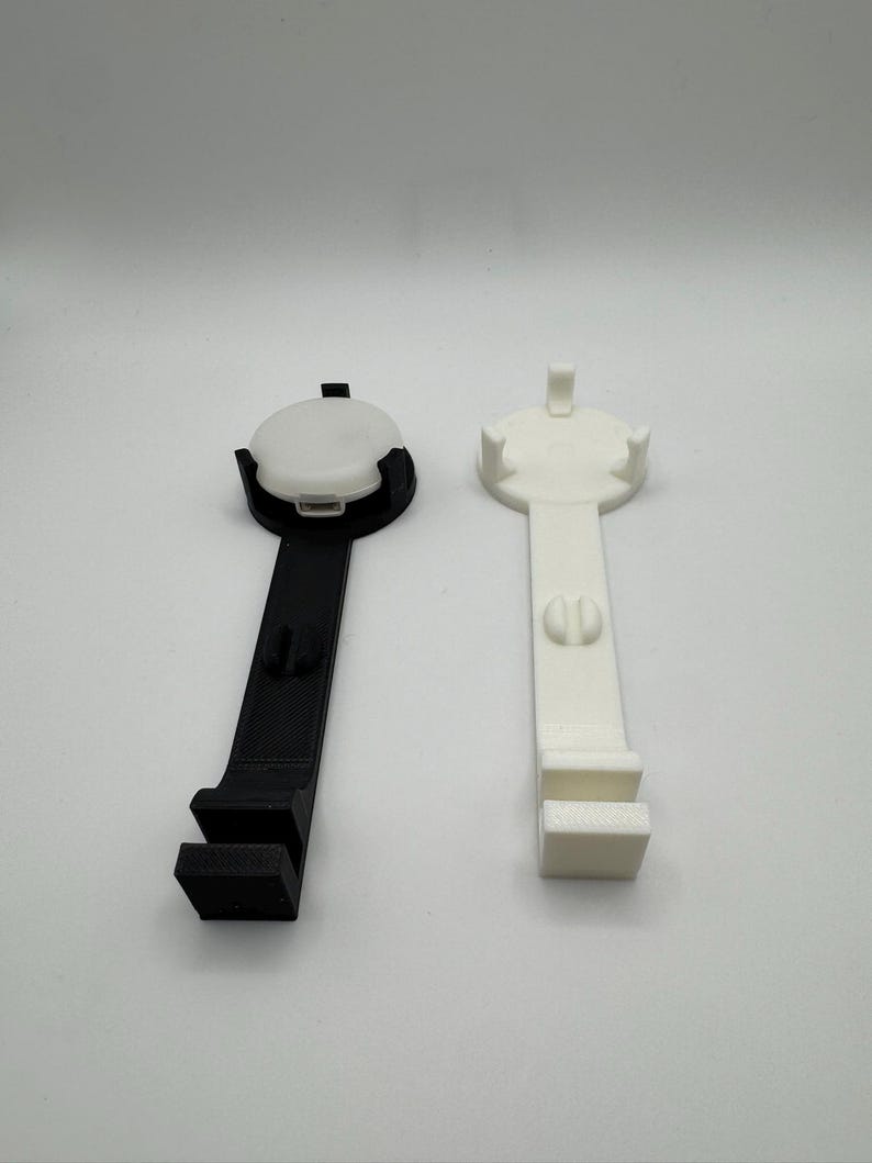 K&ouml;nnte beinhalten: Zwei 3D-gedruckte Handyst&auml;nder, einer schwarz und einer wei&szlig;. Beide St&auml;nder haben eine runde Basis und einen langen, geraden Arm mit einem rechteckigen Handyhalter am Ende.
