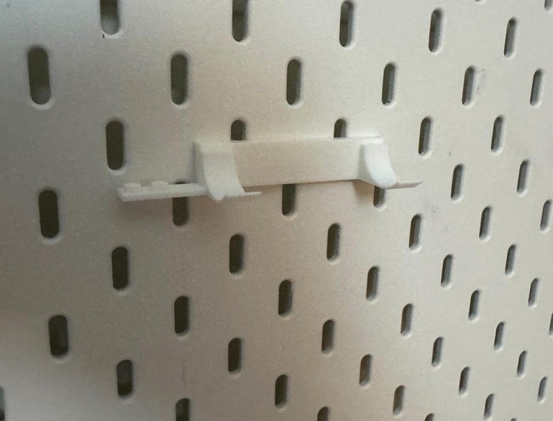 May include: White plastic pegboard with a white plastic hook attached to it.
