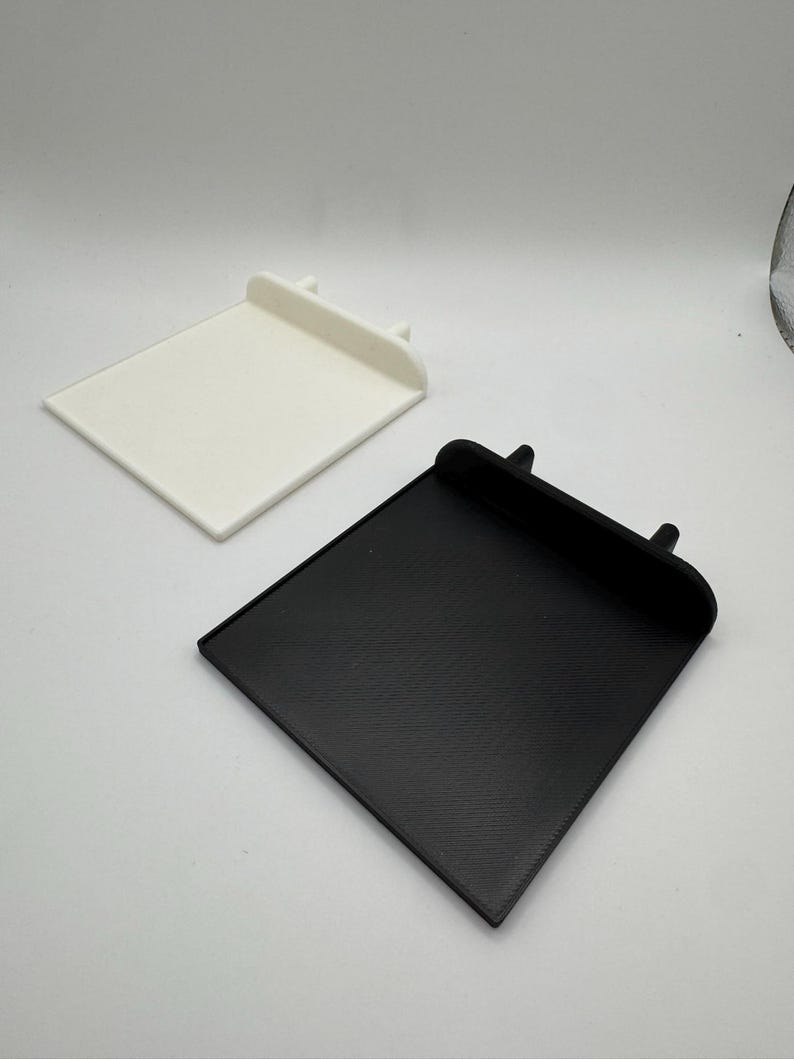 Pode incluir: Duas bandejas quadradas impressas em 3D, uma branca e outra preta. As bandejas t&ecirc;m uma borda elevada ao redor da borda e duas pequenas sali&ecirc;ncias na parte de tr&aacute;s.