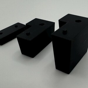 May include: Three black plastic corner brackets, two are L-shaped and one is a straight piece.