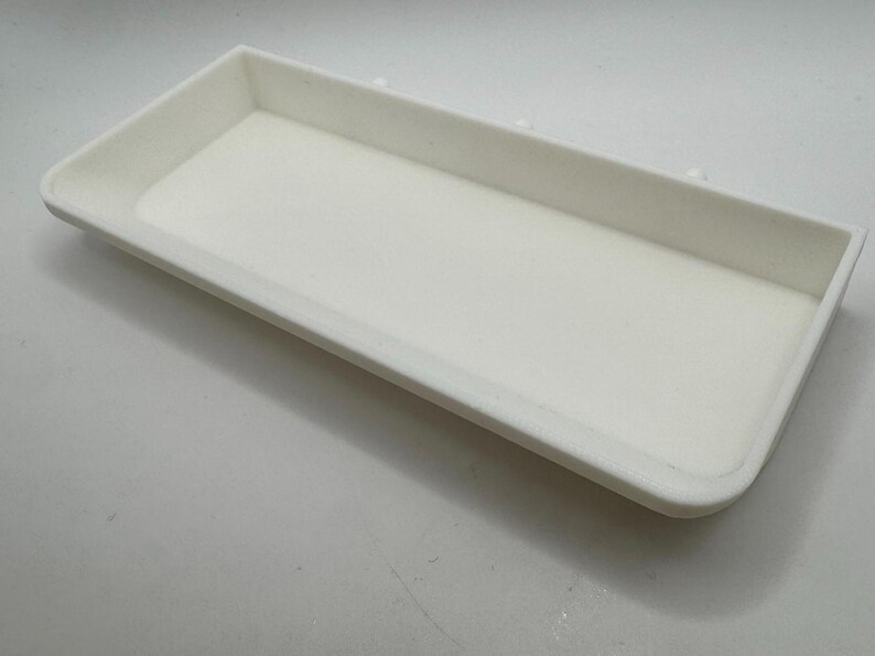 Puede incluir: Una bandeja rectangular blanca con una superficie lisa. La bandeja est&aacute; hecha de un material ligero y tiene un borde ligeramente elevado.