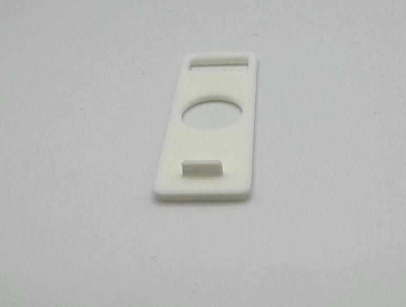Pu&ograve; includere: Supporto per telefono in plastica bianca con un ritaglio per un telefono e un piccolo labbro sul fondo.