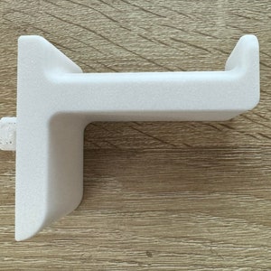 Pu&ograve; includere: Un supporto a parete bianco a forma di L per cuffie. Il supporto ha una superficie strutturata e un piccolo perno laterale per il montaggio. Il design &egrave; semplice e moderno, adatto per organizzare le cuffie.