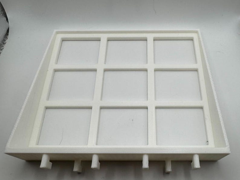Op de afbeelding: Witte plastic bak met negen vierkante vakken. De bak heeft een verhoogde rand en kleine voetjes aan de onderkant.